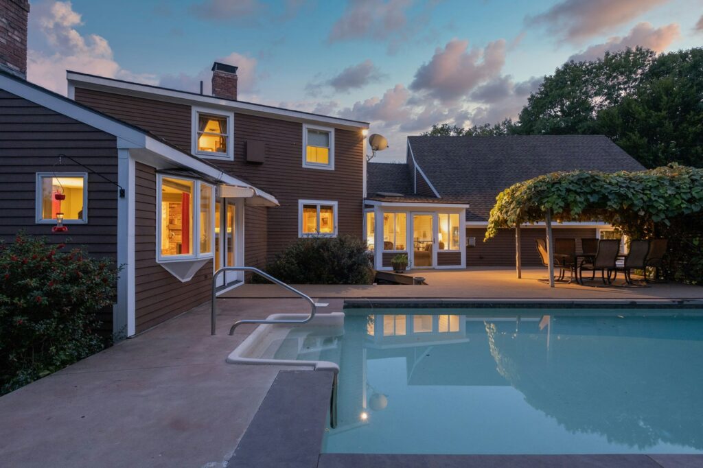 Modern cozy lit house and a pool under a cloudy sky in the evening