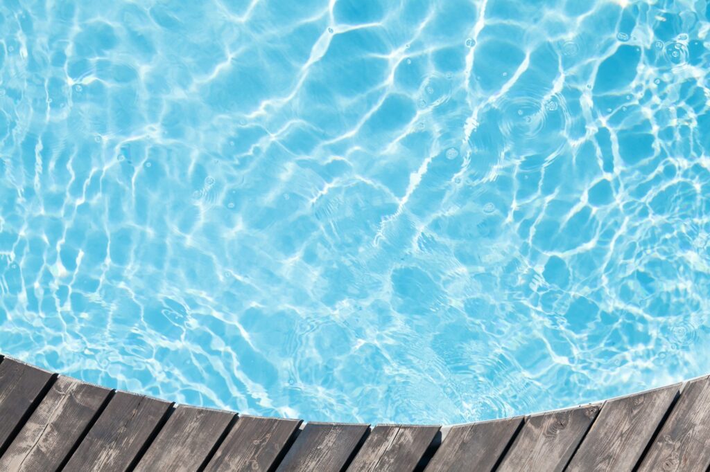 Poolside wooden deck and blue water of pool