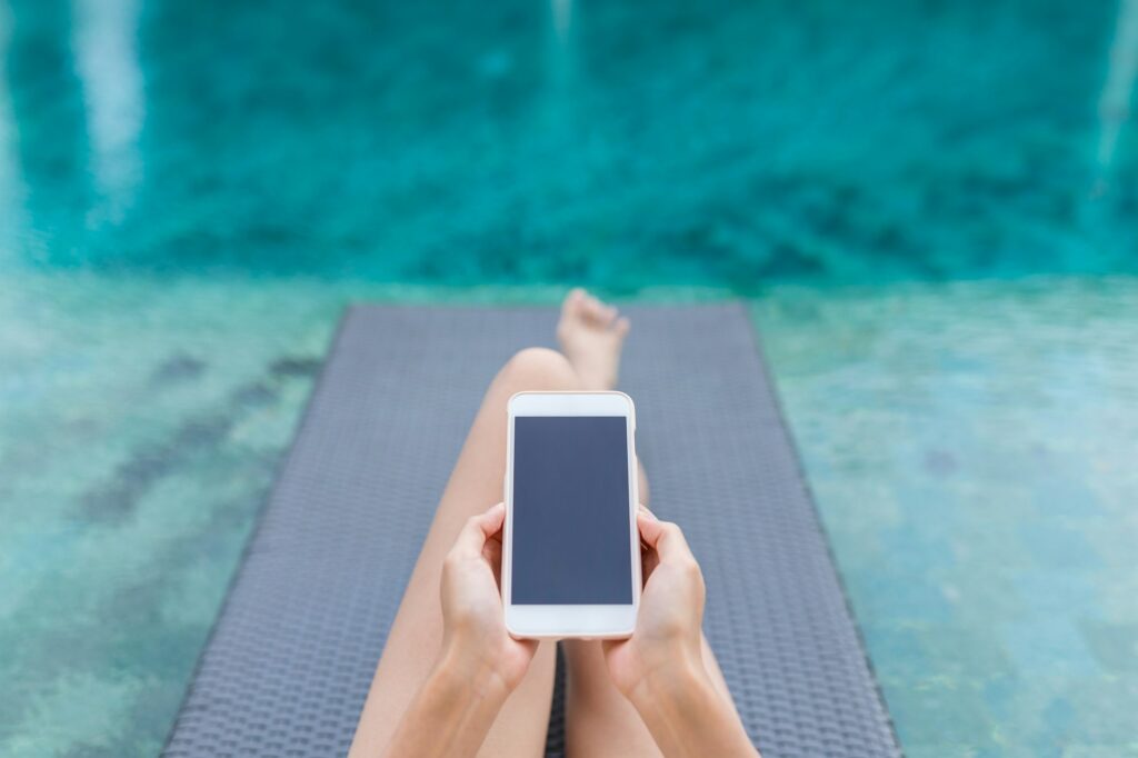 Woman working on mobile phone at poolside on holiday