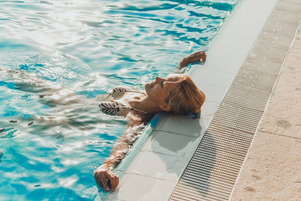 Mujer Joven Relajándose en la Piscina Durante el Verano
