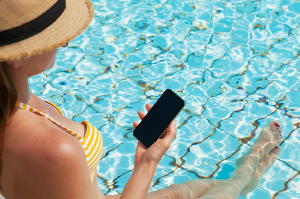 Young woman using smartphone near a swimming pool