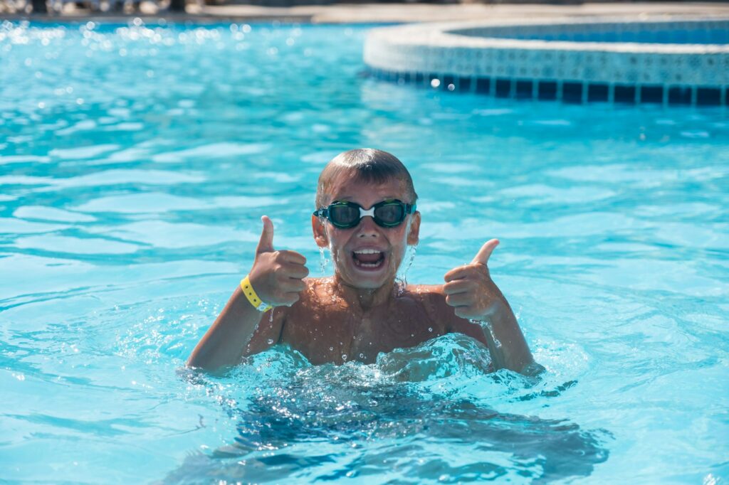 A handsome guy in swimming goggles dives in a pool of clean clear water. Active rest on vacation.