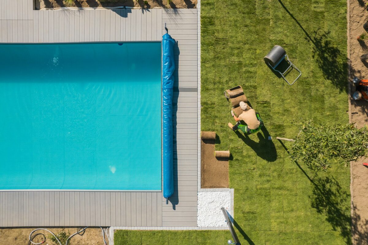 Aerial View of a Poolside and Grass Turfs Installation por qué es importante cubrir la piscina con cubrepiscinas