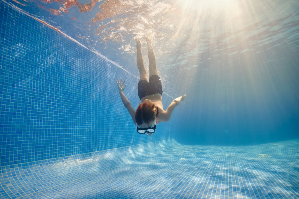 Boy diving in clear swimming pool